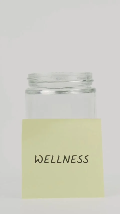 Wellness text or word on yellow sticky note attached to glass jar with hand Stock Footage 311806380