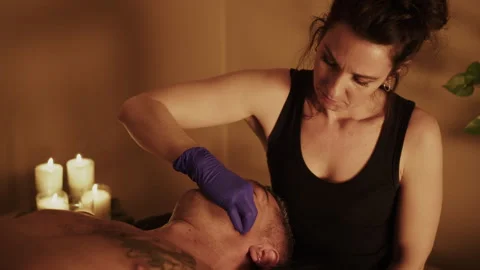 Wellness therapist using gloved hand for precise facial and jaw muscle treatment Stock Footage 321486671