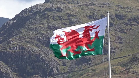 Welsh flag waving in the beautiful landscape of Llanberis, Snowdonia in Wales at Stock Footage 94617232