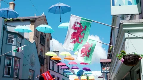 Welsh flags in front of colourful hanging umbrella canopy Stock Footage 190077049