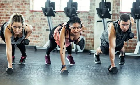Were all performing at the same level. a fitness group using dumbbells in their Stock Photos
