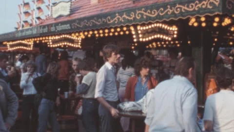 West Berlin - 1983: Crowd gathers at an amusement park food kiosk in the summer Stock Footage 291928637