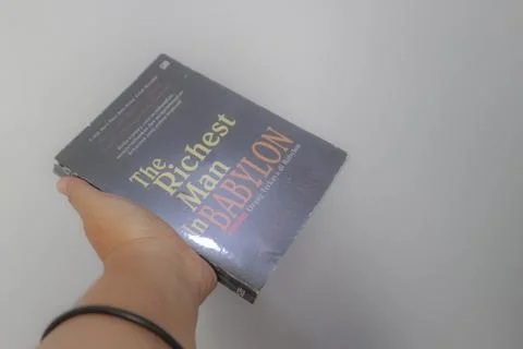 West Java, Indonesia on July 2022. A hand is holding a novel The Richest Ma.. Stock-Fotos