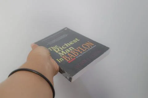 West Java, Indonesia on July 2022. A hand is holding a novel The Richest Ma.. Fotos de archivo