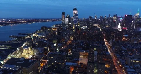 West Side waterfront leads toward Lower Manhattan lights at dusk Stock Footage 83770279