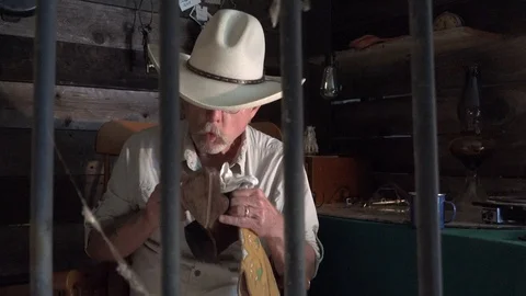 Western sheriff as seen from the jail cell looking at pocket watch Stock Footage 92745782