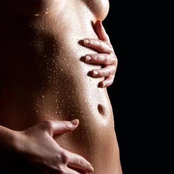 Wet belly of a nude slim woman Stock Photos