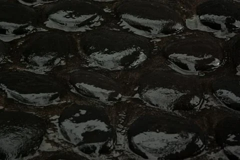Wet black cobblestone pavement of smooth volcanic stones, texture, top view,  Stock Photos