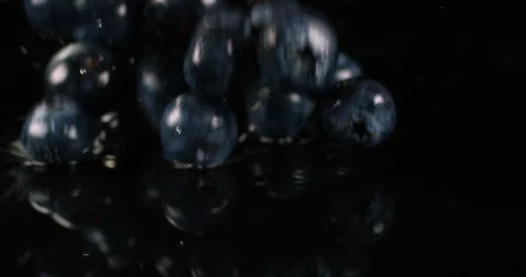 Wet blueberries falling on a black surface with water splashes. Close up view Stock Footage 108653022
