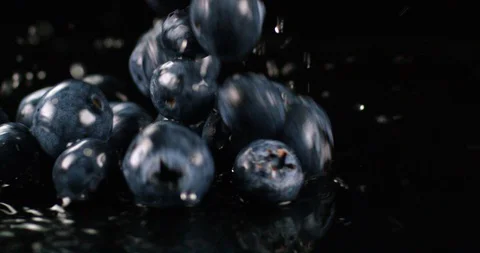 Wet blueberries falling on a black surface with water splashes. Close up view Stock Footage 108653700