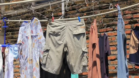 Wet clothes drying under the morning sun Stock Footage 282065579