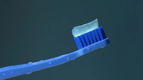 Wet, covered with flags, a blue plastic toothbrush with toothpaste Stock Footage 306591623