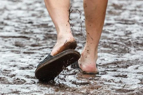 Wet feet splashing mud in shallow puddle Stock Photos