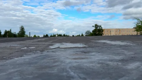 Wet flat roof surface with rain puddles under a cloudy blue sky Stock Footage 337553142