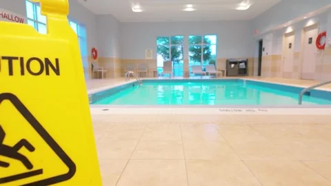 Wet floor caution sign by a pristine indoor swimming pool with serene lighting Stock Footage 321133027