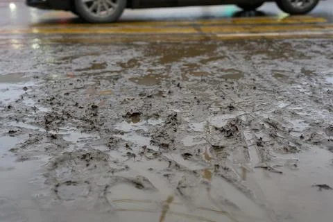Wet ground covered in mud after a rainstorm near a busy street Stock Photos