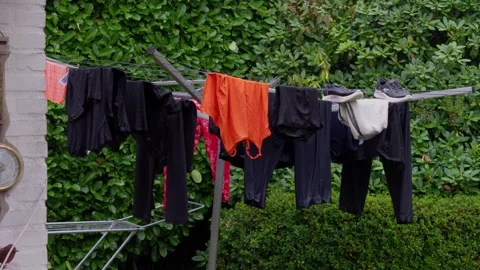 Wet laundry drying on rotary clothesline beside brick wall in Budel garden Stock Footage 346321593