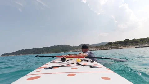 Wet man climbs back onto stand-up paddleboard after falling into the sea. Real Stock Footage 313843746