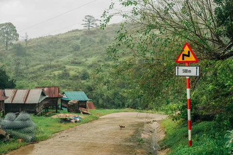 Wet mountain road with sharp bend warning sign Fotos de archivo