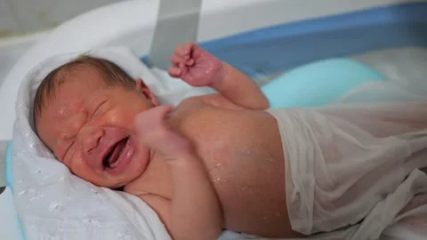 Wet newborn baby with crying expression during bathing Stock Footage 312760751