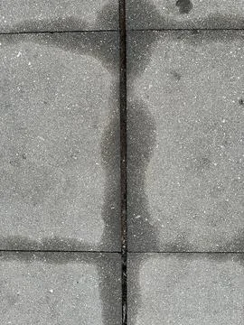 Wet patch on grey concrete pavement tiles, high angle view texture Stock Photos