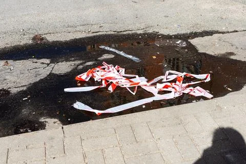Wet pavement with caution tape. Postincident urban scene with spilled paint and Stock Photos