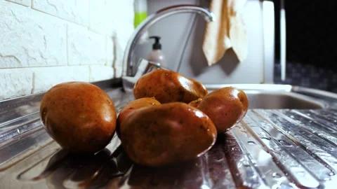 Wet potatoes rolling across the kitchen sink close up Stock Footage 263149136