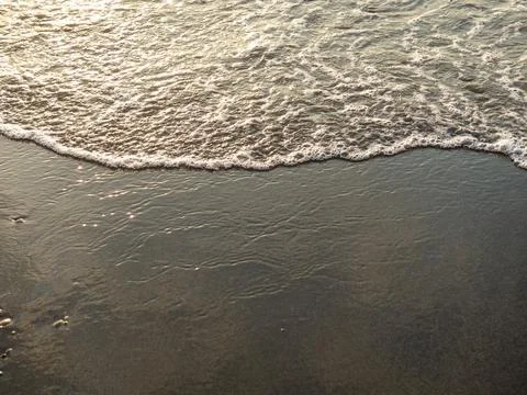 Wet sand of the beach in the rays of the setting sun. The silence of the wild Stock Photos
