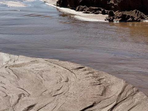 Wet Sand Patterns and Flowing Water on Natural Beach Shore Stock Photos