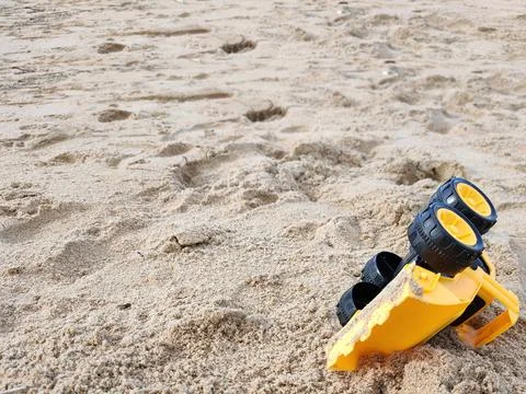 Wet sandy beach background with yellow toy excavator Stock Photos
