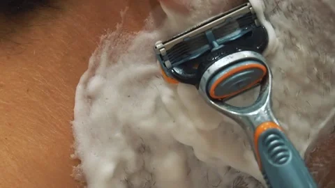 Wet shaving a man's face with a poor shaving razor. Hair pulling, close-up Stock Footage 141395993
