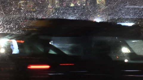 Wet snow falling in city intersection at night wth car traffic Stock Footage 99533108