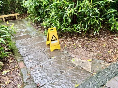 Wet Stone Pathway with Caution Sign in Lush Garden Foto stock