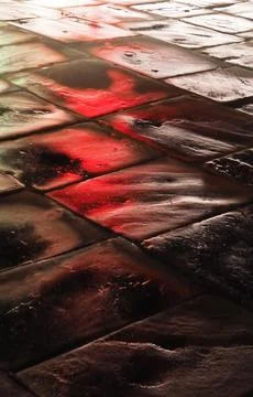 A wet stone pavement with the reflection of red neon light Stock Photos
