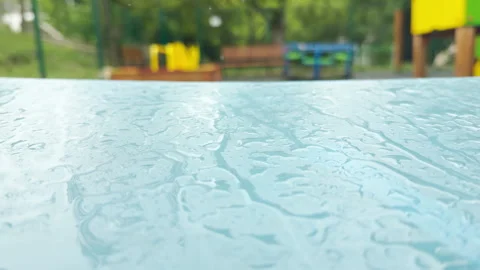 Wet swing seat sways gently on an empty playground after a heavy rain Stock Footage 336093489