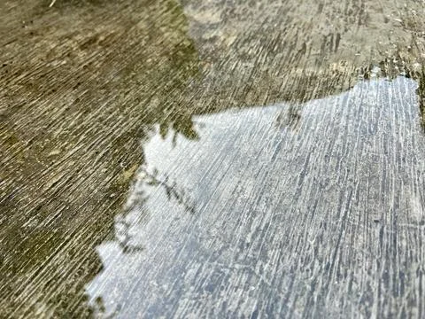 Wet Textured Concrete Ground Surface With Water Puddle Reflecting Stock-Fotos