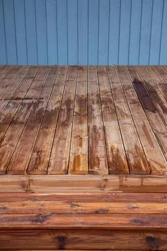 Wet timber deck with damp planks and blue painted wall cladding 스톡 사진