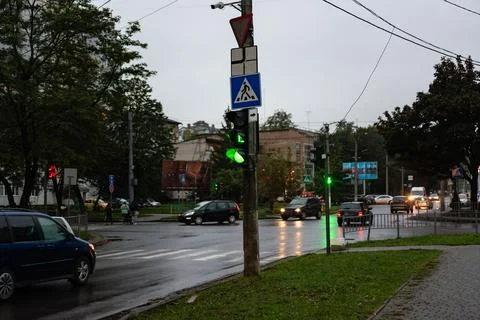 Wet twilight reveals a bustling intersection with green lights guiding cars.. Stock Photos