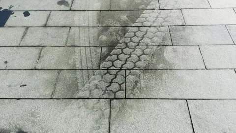 Wet tyre track drying on granite paving in the sun Stock Footage 343126924