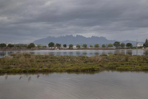 Wetlands reflecting mountain range under cloudy sky in spain Stock Photos