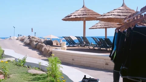 Wetsuits hanging on the beach, shot of part of wetsuits hanging on a hanger. The Stock Footage 240201007
