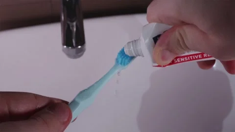 Wetting blue toothbrush under running tap water and applying toothpaste Stock-Footage 344877030
