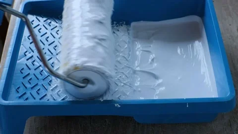 Wetting the roller in the white paint in a paint tray Stock Footage 197785816