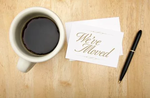 We've Moved Note Card, Pen and Coffee Cup on Wood Background. Stock Photos