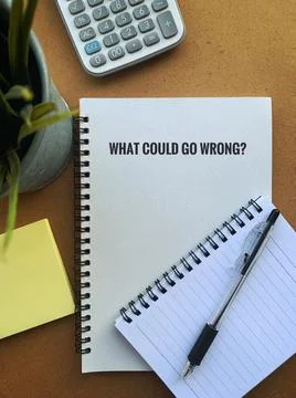 What could go wrong text on a note pad with pen, plant, calculator and sticky Stock Photos