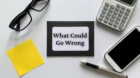 What could go wrong text on notepad with glasses, calculator, phone and yellow Foto stock