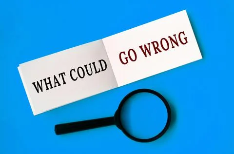 What could go wrong text on notepad with magnifying glass on blue background. Foto stock