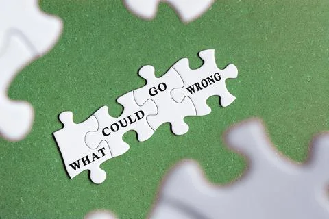 What could go wrong text on white jigsaw puzzle with some missing pieces. Stock Photos
