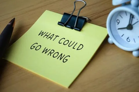 What could go wrong text on sticky note with alarm clock background Stock Photos