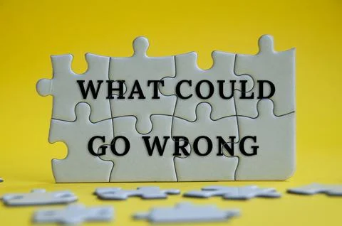 What could go wrong text on jigsaw puzzle on yellow cover background. Stock Photos